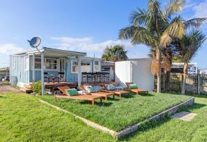 a house with benches on the grass in front of it at The Little Blue Bach in Oneroa Village by Waiheke Unlimited in Oneroa