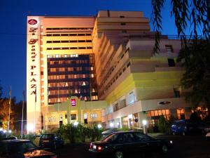duży budynek z zaparkowanymi przed nim samochodami w obiekcie Le Grande Plaza Hotel w Taszkiencie