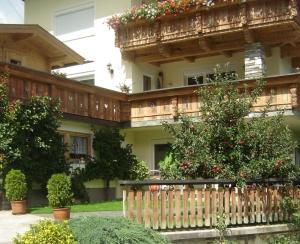 una valla de madera frente a un edificio con flores en Ferienwohnung Kainer Carina, en Ried im Zillertal