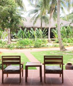 two chairs and a table in front of a park at Peppercorn Beach Resort in Phú Quốc