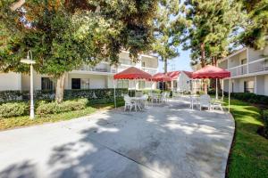 a patio with red umbrellas and tables and chairs at Motel 6-Santa Ana, CA - Irvine - Orange County Airport in Santa Ana
