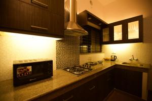 a kitchen with a stove top oven next to a sink at Anchorage Serviced Apartments in Cochin
