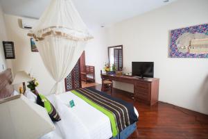 a bedroom with a bed and a desk with a television at Amata Resort & Spa, Ngapali Beach in Ngapali