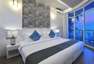 a white bedroom with a large bed and a window at Velana Beach Hotel Maldives in Maafushi