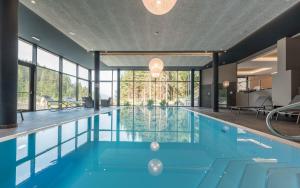 a swimming pool with blue water and large windows at Hotel Rosengarten in Nova Levante