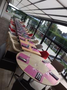 a long row of tables in a room with windows at Hotel-Restaurant Lann Roz / Côte Cuisine in Carnac