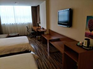 a hotel room with two beds and a flat screen tv at Goldmet Inn Taiyuan Dananamen in Taiyuan