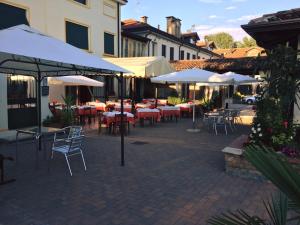 un patio con tavoli, sedie e ombrelloni di Agriturismo La Scacchiera a Padova