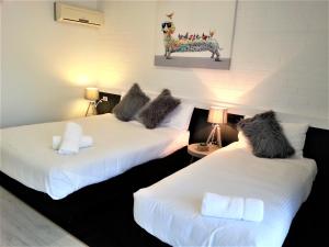 two beds with faux fur pillows on them in a room at Kurri Motor Inn in Kurri Kurri