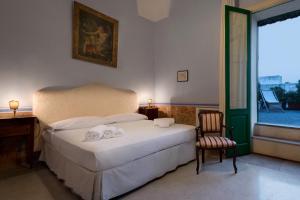 a bedroom with a bed and a desk and a window at Palazzo Laura in Morciano di Leuca