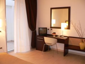 a room with a desk with a mirror and a television at Il Grillo Hotel in Pulsano