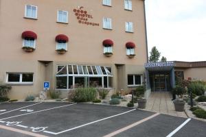 a hotel with a parking lot in front of it at Logis Hotel des C&eacute;pages in Arbois
