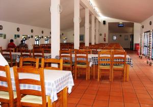 una sala da pranzo con tavoli e sedie in legno di Parque de Campismo Orbitur Sitava Milfontes a Malhadinhas