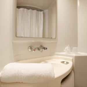 a white bathroom with a sink and a mirror at Premiere Classe Nevers Varennes Vauzelles in Varennes Vauzelles