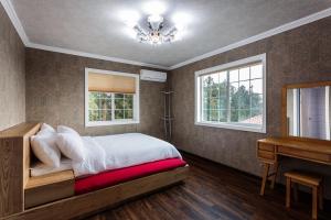 a bedroom with a bed and a desk and windows at Mar En Luz in Seogwipo