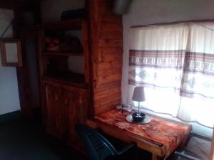 a lamp on a wooden table in a room with a window at Joy River Backpackers in Moremela