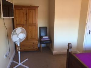 a room with a bedroom with a fan and a dresser at 287 Green Lanes in London