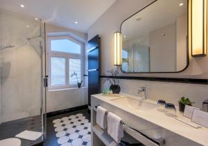 a bathroom with a sink and a shower and a mirror at Hotel Am Leuchtturm in Warnemünde