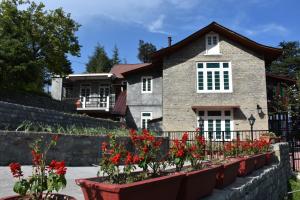 a house with red flowers in front of it at Deodar Manor - Guest House Khajjiar in Khajjiar  +46 photos