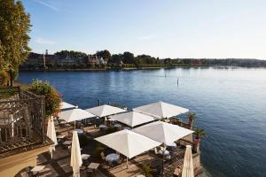 a group of tables with umbrellas next to a river at Steigenberger Inselhotel in Konstanz