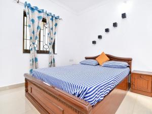 a bedroom with a bed with a blue and white comforter at Esha Apartment in Calangute