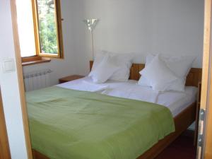 a bed with a green blanket and white pillows at Villa Una in Sarajevo