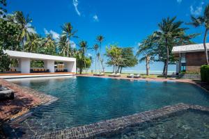 a swimming pool in front of a house with palm trees at Tolani Resort Koh Samui in Lamai