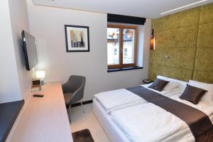 um quarto com uma cama, uma secretária e uma televisão em Andantino by Schladmingurlaub em Schladming