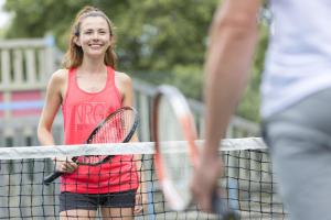 een jong meisje op een tennisbaan met een racket bij Camping Officiel Siblu Les Dunes de Contis in Saint-Julien-en-Born