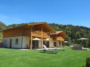 een huis met stoelen en parasols op een gazon bij Gasserhof Chalets in Meltina