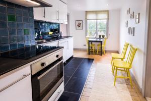 a kitchen with white cabinets and a table with yellow chairs at Eneby Gård Apartments in Sköldinge