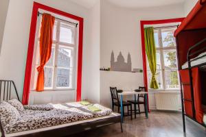a bedroom with a bed and a table and two windows at Pal's Mini Hostel in Budapest