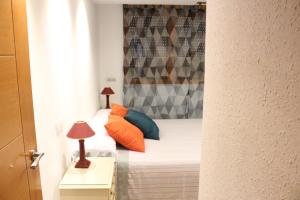 アリカンテにあるApartamento de Silviaのベッドルーム1室(オレンジと青の枕が付いたベッド1台付)
