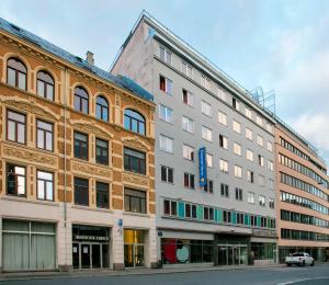 a building on a street next to some buildings at Comfort Hotel Xpress Youngstorget in Oslo