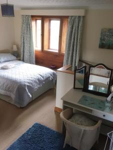 1 dormitorio con cama, espejo y escritorio en Pellcroft Cottage, en Holmfirth