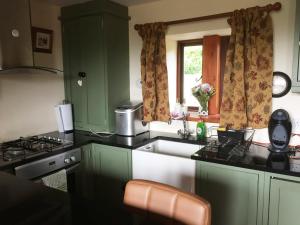 a kitchen with green cabinets and a sink and a window at Pellcroft Cottage in Holmfirth