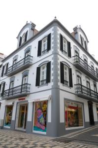 a large white building with black shuttered windows at Edifício Charles 203 in Funchal