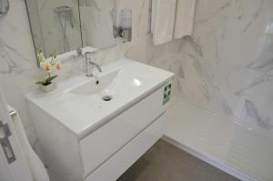 a white bathroom with a sink and a mirror at Edifício Charles 203 in Funchal