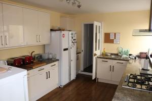 a kitchen with white cabinets and a white refrigerator at Norfolk Guest House in Bristol