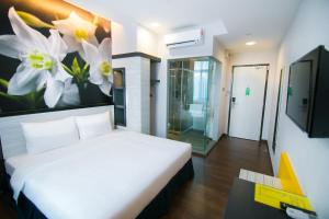 - une chambre avec un lit et un tableau de fleurs sur le mur dans l'établissement INDRA HOTEL - BOUTIQUE SUITES, à Ipoh
