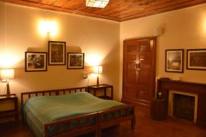 a bedroom with a bed and two lamps and a fireplace at Deodar Manor - Guest House Khajjiar in Khajjiar 