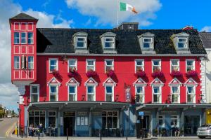 un edificio rosso con finestre bianche e una bandiera in cima di McSweeney Arms Hotel a Killarney