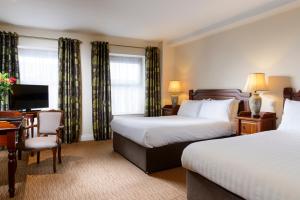 una camera d'albergo con 2 letti e una scrivania di McSweeney Arms Hotel a Killarney