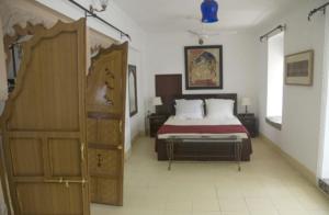 1 dormitorio con 1 cama y puerta de madera en Hotel Bundi Haveli, en Bundi