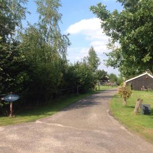 a winding road with a barn and a house at De Bolderie in Markelo