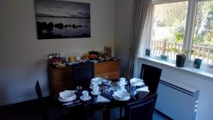 a dining room with a table with chairs and a kitchen at Bluebell Cottage in Tarbert