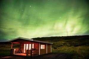 a small cabin with the aurora in the sky at Ásgeirsstaðir Holiday Homes in Ásgeirsstaðir
