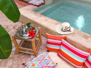 a table and pillows next to a swimming pool at Riad Dar Balthazar in Marrakech