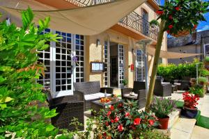 une terrasse avec des chaises en osier et des fleurs devant une maison dans l'établissement Hôtel Le Lascaux, à Montignac