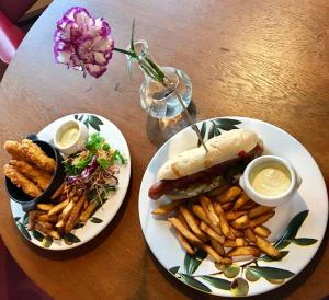 a table with two plates of food with a sandwich and french fries at Motel Käpylä in Keminmaa